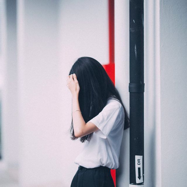 En flicka står mot en vägg.